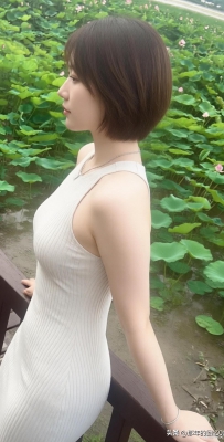 她站在荷花池旁，穿着白色连衣裙。